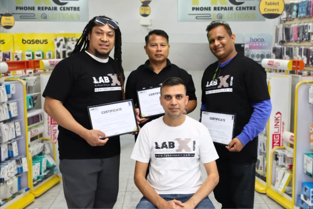 Bharat Dhingra with graduating course students holding accredited repair certificates inside St Marys workshop